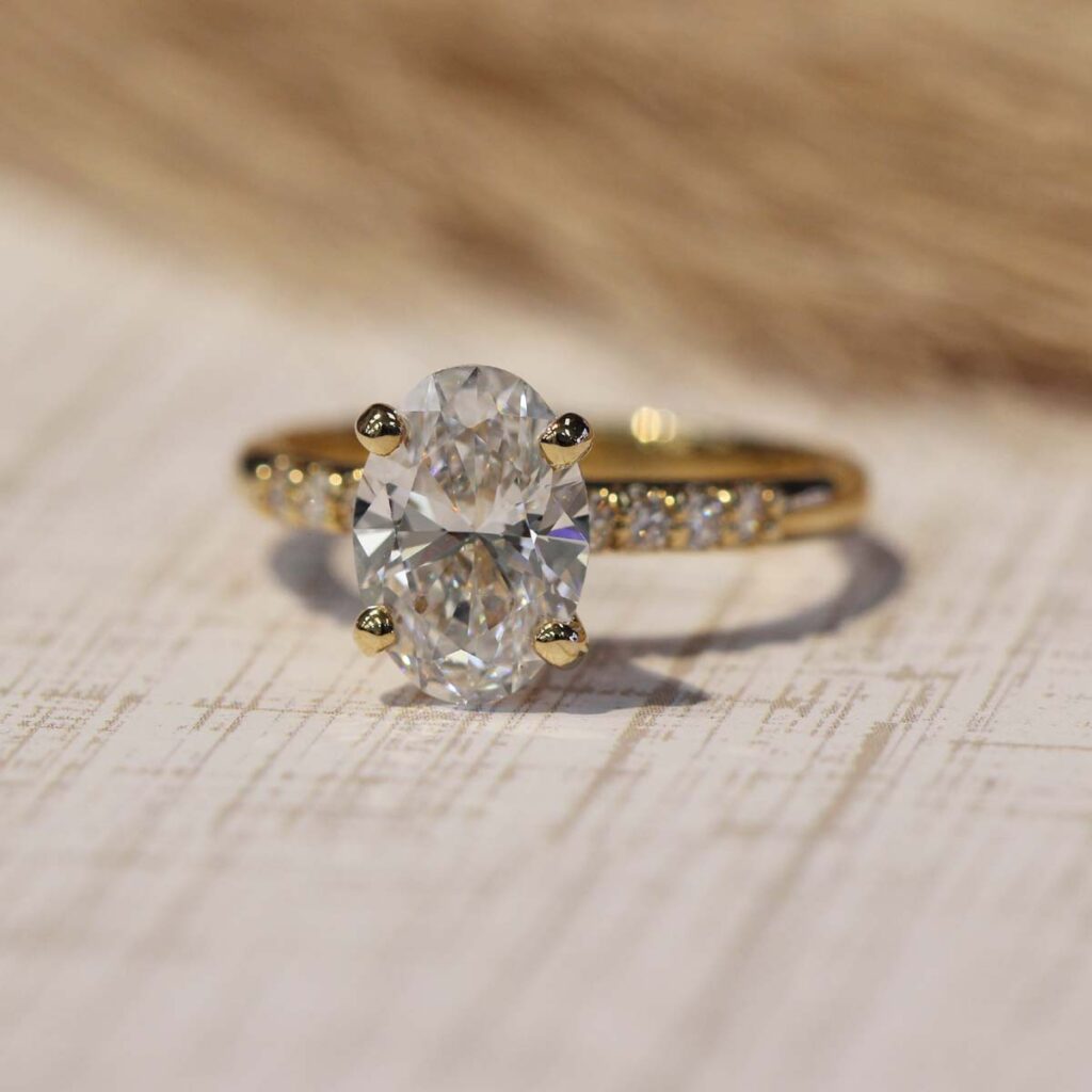 Three-stone oval diamond engagement ring in yellow gold, a most popular engagement ring style for modern brides.